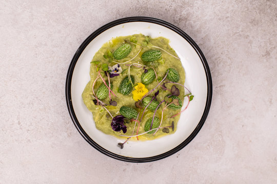 Avocado mousse served with cucamelon and micro greens. Healthy vegan food.