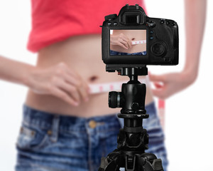 Asian vlogger measuring waist behind camera, social media concept