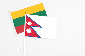 Nepal and Lithuania stick flags on white background. High quality fabric, miniature national flag. Peaceful global concept.White floor for copy space.
