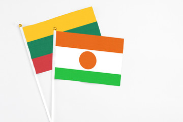 Niger and Lithuania stick flags on white background. High quality fabric, miniature national flag. Peaceful global concept.White floor for copy space.