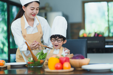 Happy family. Asian mother and son in the kitchen. The mother and son help make a vegetable salad by teaching children to make healthy salad dishes for dinner.