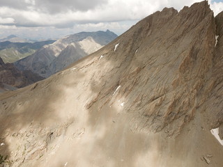 vue aérienne de sommet de haute montagne rocailleux avec strates géologiques et neiges...