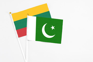 Pakistan and Lithuania stick flags on white background. High quality fabric, miniature national flag. Peaceful global concept.White floor for copy space.