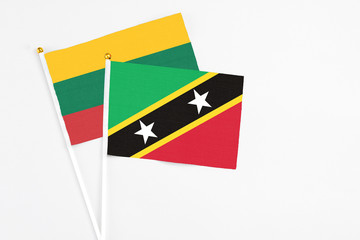 Saint Kitts And Nevis and Lithuania stick flags on white background. High quality fabric, miniature national flag. Peaceful global concept.White floor for copy space.