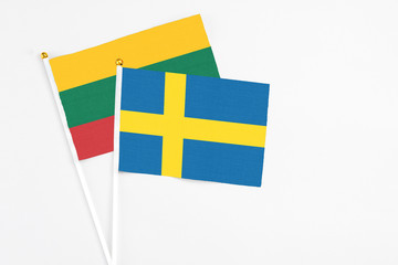 Sweden and Lithuania stick flags on white background. High quality fabric, miniature national flag. Peaceful global concept.White floor for copy space.