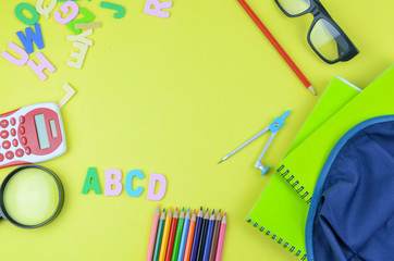 Student backpack and various school supplies. Studying, education and back to school concept. Yellow background and selective focus.