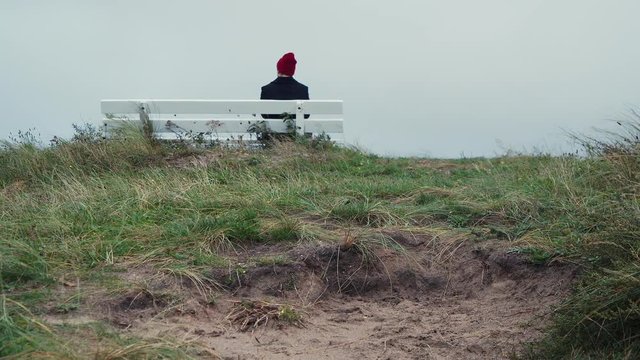 Man sitting at the bench in National Park. Cloudy outumn day, loneliness. 