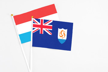 Fototapeta premium Anguilla and Luxembourg stick flags on white background. High quality fabric, miniature national flag. Peaceful global concept.White floor for copy space.