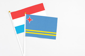 Aruba and Luxembourg stick flags on white background. High quality fabric, miniature national flag. Peaceful global concept.White floor for copy space.
