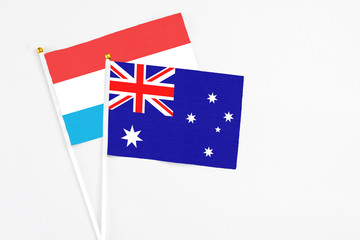 Fototapeta premium Australia and Luxembourg stick flags on white background. High quality fabric, miniature national flag. Peaceful global concept.White floor for copy space.