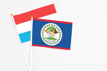 Belize and Luxembourg stick flags on white background. High quality fabric, miniature national flag. Peaceful global concept.White floor for copy space.