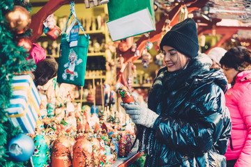 Fototapeta na wymiar Positive female buying New Year souvenirs on fairground