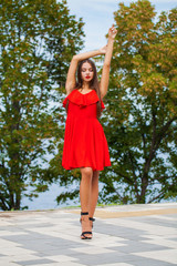 Young beautiful woman in red dress on the summer street
