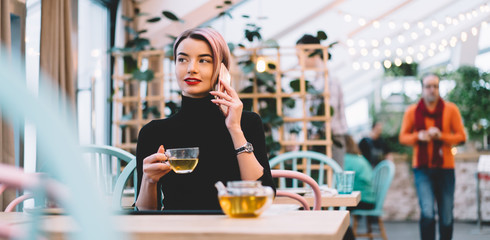 Trendy content modern woman talking on phone at cafe