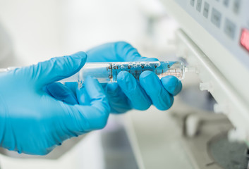 Analyst is Drawing sample from dissolution test of semi automatic type tester and wear the safety protective gloves.