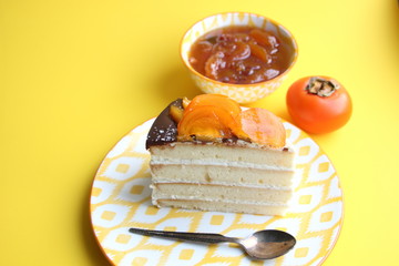 Piece of cake with fresh persimmon on yellow background