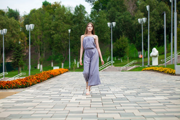 Young beautiful blonde woman in summer dress posing in summer park