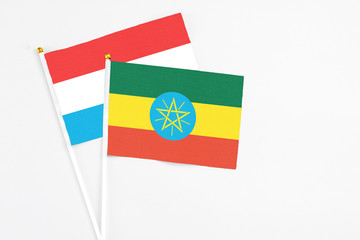 Ethiopia and Luxembourg stick flags on white background. High quality fabric, miniature national flag. Peaceful global concept.White floor for copy space.