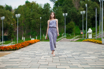 Young beautiful blonde woman in summer dress posing in summer park