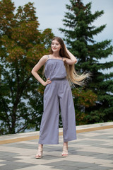 Young beautiful blonde woman in summer dress posing in summer park