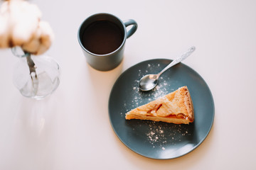 Piece of apple pie on plate with cup of coffee on white table. Breakfast with coffee and cake in cafe. food photography. 