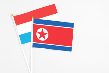 North Korea and Luxembourg stick flags on white background. High quality fabric, miniature national flag. Peaceful global concept.White floor for copy space.