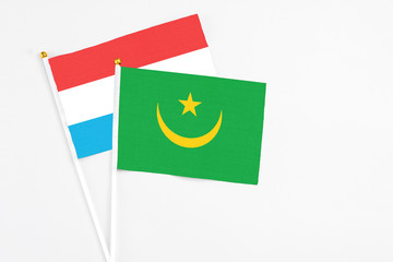 Mauritania and Luxembourg stick flags on white background. High quality fabric, miniature national flag. Peaceful global concept.White floor for copy space.