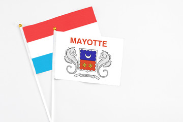 Mayotte and Luxembourg stick flags on white background. High quality fabric, miniature national flag. Peaceful global concept.White floor for copy space.
