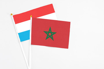 Morocco and Luxembourg stick flags on white background. High quality fabric, miniature national flag. Peaceful global concept.White floor for copy space.
