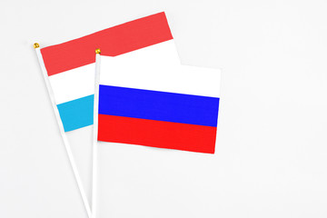 Russia and Luxembourg stick flags on white background. High quality fabric, miniature national flag. Peaceful global concept.White floor for copy space.
