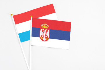 Serbia and Luxembourg stick flags on white background. High quality fabric, miniature national flag. Peaceful global concept.White floor for copy space.