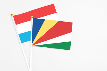 Seychelles and Luxembourg stick flags on white background. High quality fabric, miniature national flag. Peaceful global concept.White floor for copy space.