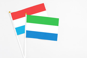 Sierra Leone and Luxembourg stick flags on white background. High quality fabric, miniature national flag. Peaceful global concept.White floor for copy space.