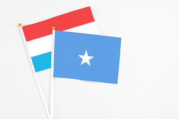 Somalia and Luxembourg stick flags on white background. High quality fabric, miniature national flag. Peaceful global concept.White floor for copy space.