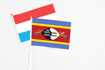 Swaziland and Luxembourg stick flags on white background. High quality fabric, miniature national flag. Peaceful global concept.White floor for copy space.
