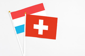 Obraz premium Switzerland and Luxembourg stick flags on white background. High quality fabric, miniature national flag. Peaceful global concept.White floor for copy space.