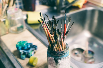 Creative workshop of the artist. Paint brushes in a jar. Many brushes for painting in one place