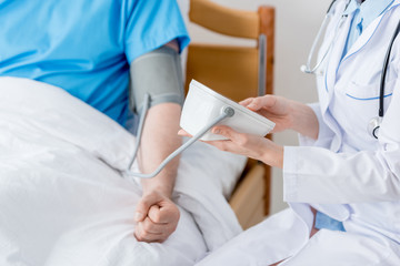 cropped view of doctor measuring blood pressure of patient in hospital
