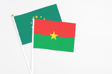 Burkina Faso and Macao stick flags on white background. High quality fabric, miniature national flag. Peaceful global concept.White floor for copy space.
