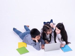Group of children reading book and using laptop,doing activity together,with happy feeling