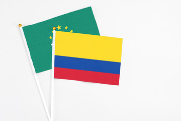 Colombia and Macao stick flags on white background. High quality fabric, miniature national flag. Peaceful global concept.White floor for copy space.