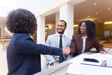 Satisfied customers thanking professional for help and good job. Business man and women sitting at table in outdoor cafe, shaking hands. Partnership concept