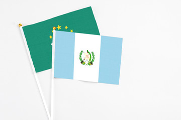 Guatemala and Macao stick flags on white background. High quality fabric, miniature national flag. Peaceful global concept.White floor for copy space.