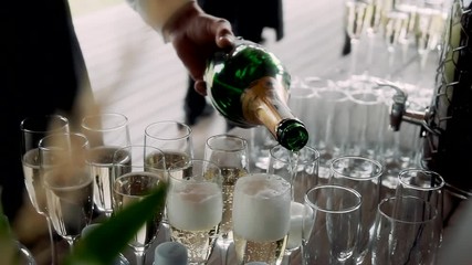 The waiter pours champagne into a glass