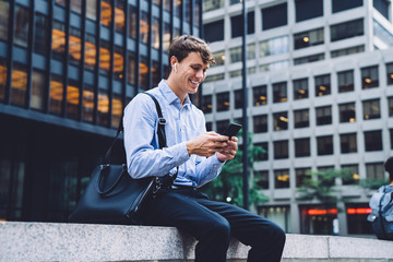 Young man chatting on phone on urban background smiling