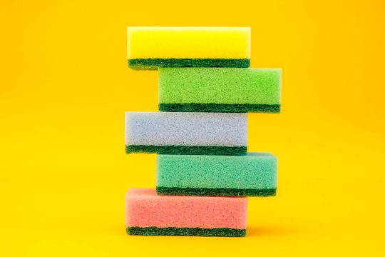 Multicolored sponges for cleaning folded pyramid on a yellow background. Space for text
