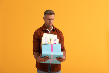 handsome man looking at gift boxes isolated on orange