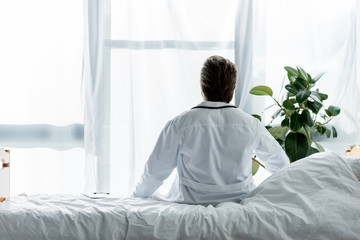 back view of doctor in white coat sitting on bed in hospital