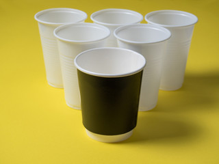 Disposable coffee cups plastic and paper stand on a yellow background.