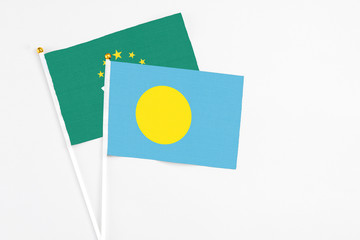 Palau and Macao stick flags on white background. High quality fabric, miniature national flag. Peaceful global concept.White floor for copy space.